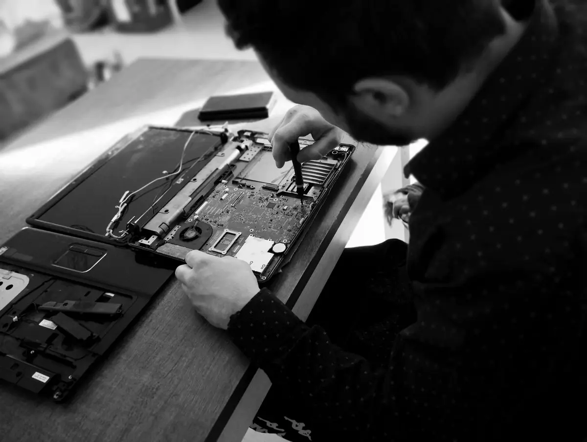 Tony Béduneau démonte un ordinateur portable dans son atelier